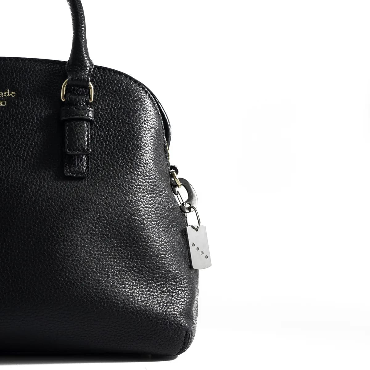 A black leather handbag with a rectangular crystal-set diamante ID tag hanging from the zip