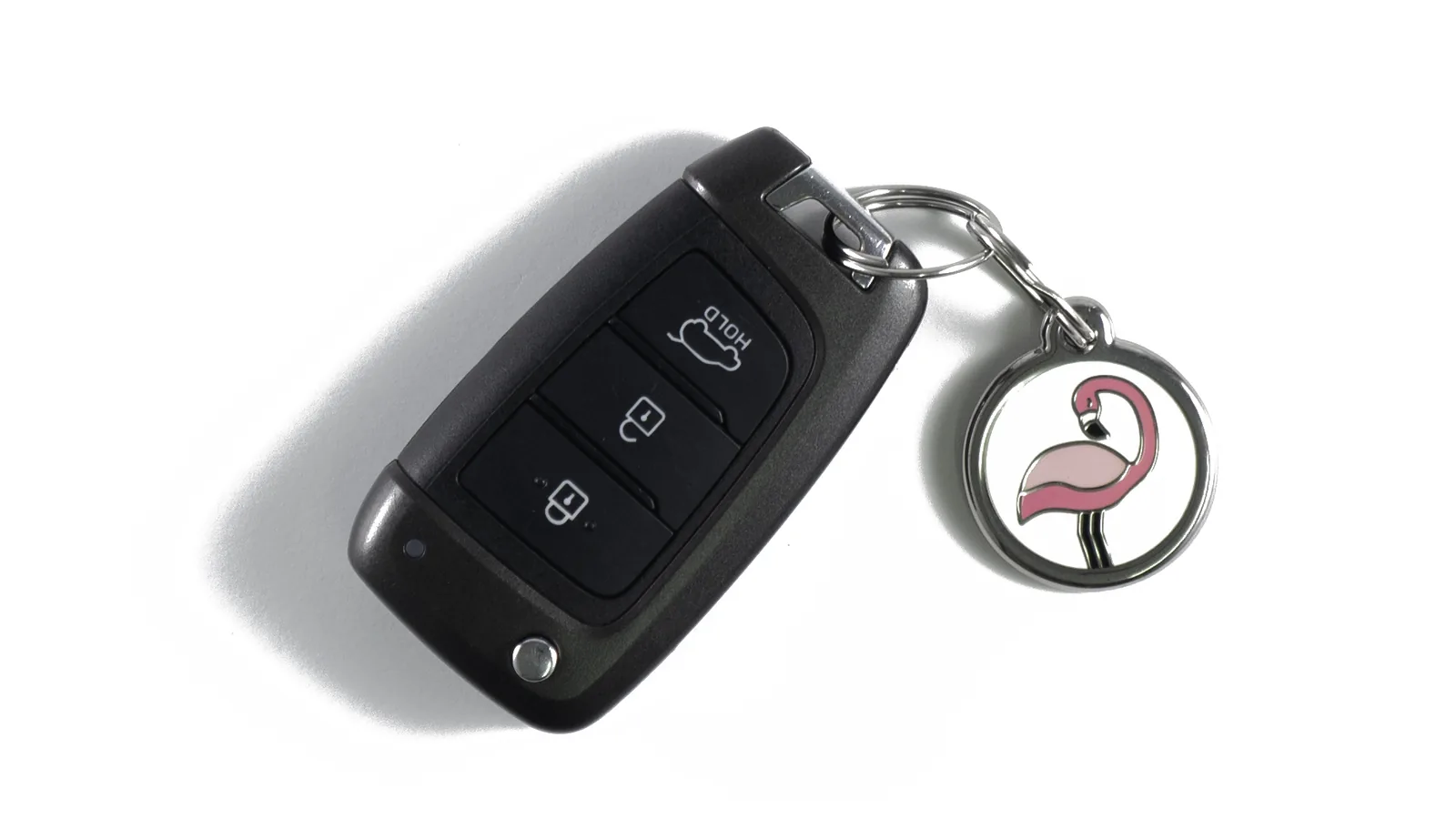 A car key fob on a key ring with a round enamel pink flamingo ID tag
