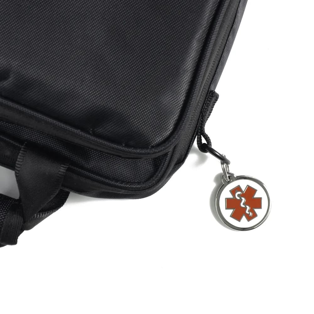 A black bag with a round enamel medical alert symbol ID tag clipped to the zip