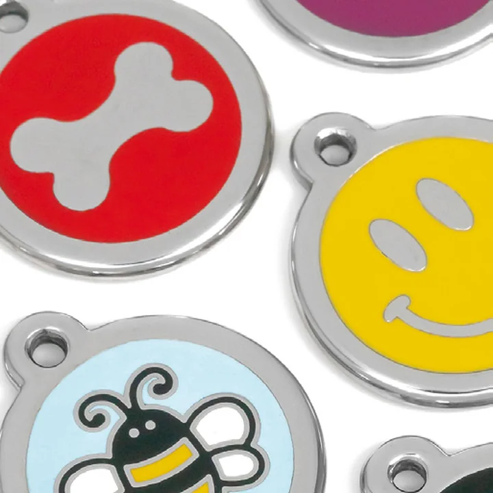A close-up of colourful Red Dingo enamel pet ID tags, including a bone, a smiley face and a bee design